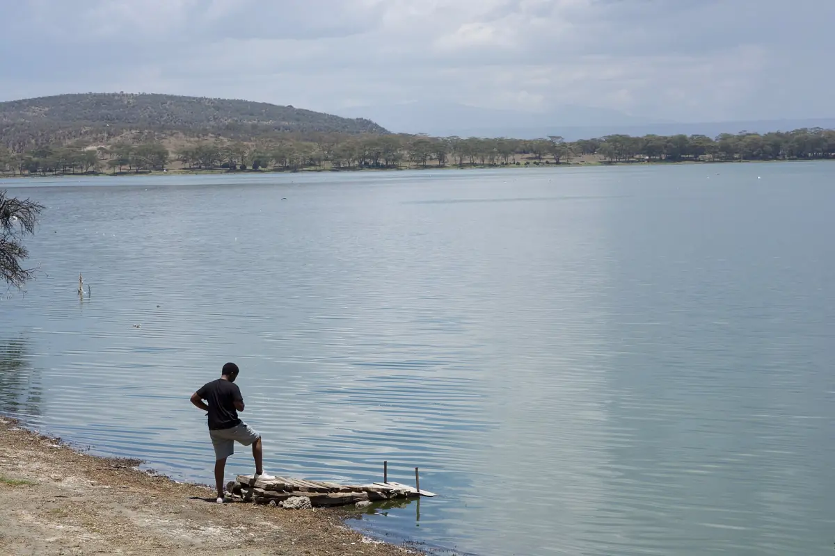 Calm water of Lake Oloiden with a person on the shore and hills beyond