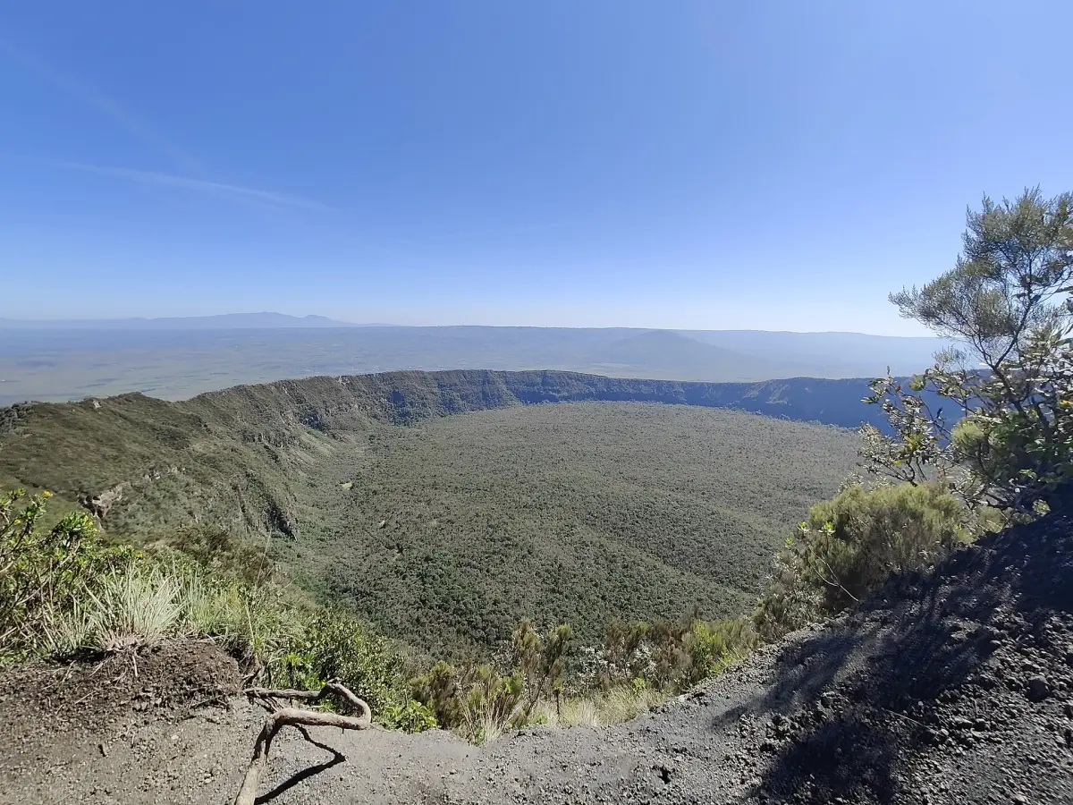 Wide crater of Longonot volcano seen from the rim under a blue sky